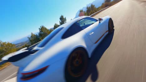 FPV-aerial-following-a-Porsche-911-GT3-along-a-scenic-highway-in-the-Spanish-countryside