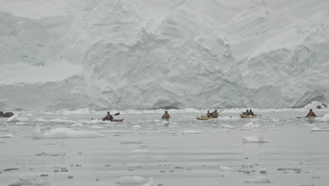 Kayaking-in-Antarctica-waters,-bay-with-ice-berg-and-floats-and-big-glacier