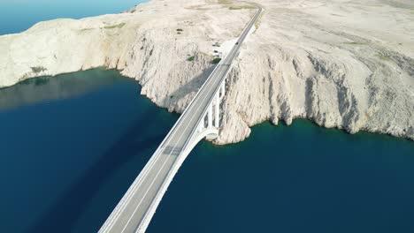 Flying-drone-backwards-the-view-over-Pag-bridge-and-white-stoney-island-on-summer-morning-in-Croatia-with-blue-Adriatic-Sea