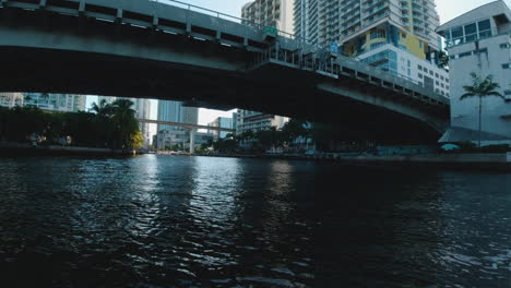 Blick-Von-Einem-Kleinen-Boot-Aus,-Das-Durch-Die-Schatten-Von-Brücken-Und-Hohen-Gebäuden-In-Den-Wasserstraßen-Von-Miami,-Florida,-Fährt