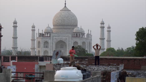 Indian-boy-retrieves-small-kite-in-view-of-Taj-Mahal-in-Agra,-India
