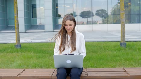 Mujer-Joven-Sentada-Afuera-Y-Trabajando-En-Una-Laptop,-En-Cámara-Lenta