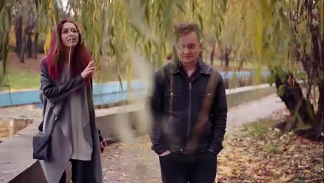 Romantic-young-couple-walking-under-the-tree-in-autumn-park-during-the-day.-The-blanket-of-golden-leaves-on-the-ground.-Warm-weather-in-autumn