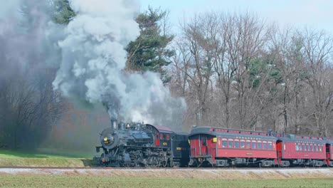 A-View-of-a-Steam-Passenger-Train-Waiting-For-a-Second-Steam-Passenger-Train-to-Pass,-Blowing-Smoke-and-Steam-on-a-Winter-Day
