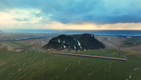 Aerial-landscape-view-of-Petursey-Mountain,-Iceland,-with-a-dramatic-cloudscape,-at-sunset