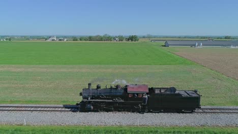 A-Drone-Side-View-of-a-Steam-Locomotive-Traveling-by-Itself-on-a-Test-Run-Thru-Rural-Countryside-on-a-Single-Track,-With-Engineer-and-Fireman-Watching,-in-Slow-Motion-on-a-Spring-Day
