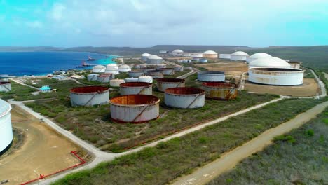 4k-Aerial-reveal-of-oil-storage-tanks-and-silos-next-to-ocean,-Bullenbaai-Oil-Terminal-in-Curacao