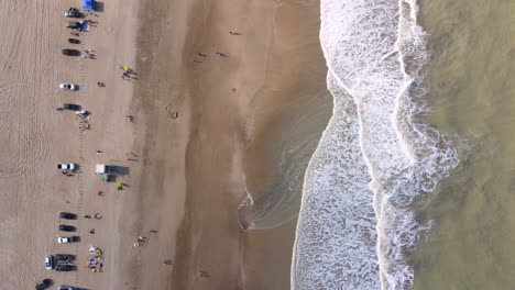 Static-top-down-drone-shot-of-a-beach-in-Cariló,-Argentina-with-waves-crashing-on-the-shore