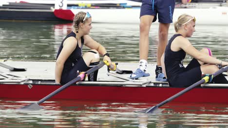 Two-women-in-jerseys-stepping-off-the-pier-into-a-racing-double-scull