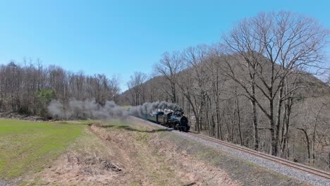 Aerial-View-of-EBT's-Narrow-Gauge-Restored-Antique-Steam-Passenger-Train-Approaching,-Going-Upgrade-With-Steam-and-Smoke-on-a-Clear-Sunny-Day