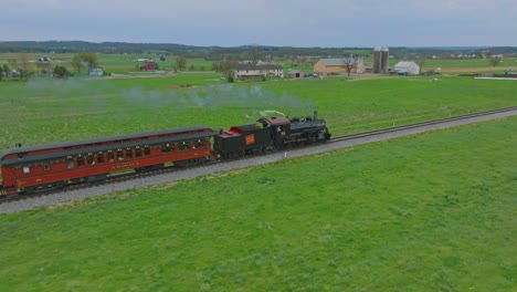 A-Drone-View-from-Behind-of-a-Steam-Passenger-Train-Traveling-Thru-Farmlands-in-Slow-Motion-on-a-Spring-Day