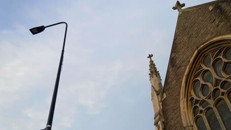 Low-angle-shot-of-pigeons-flying-around-a-church-and-lamppost-in-Cardiff