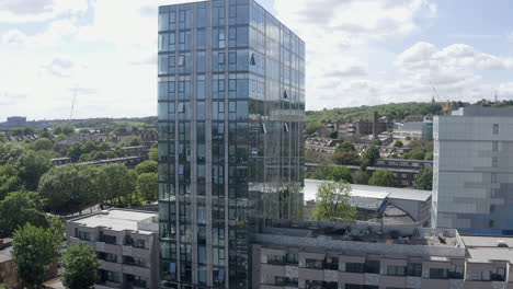 City-aerial-descent:-Shiny-glass-apartment-building-in-London,-England