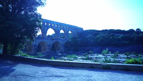 Shot-of-the-Pont-du-Gard-in-France-in-the-evening-behind-some-trees-in-nature-over-a-river