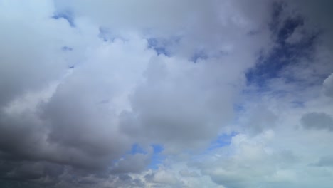 Flauschige-Wolken,-Die-Sich-Von-Der-Kamera-Entfernen,-Und-Flecken-Blauen-Himmels,-Langzeitbelichtung,-60-facher-Zeitraffer