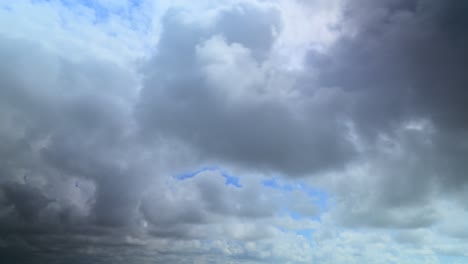 Billowing-storm-clouds-racing-past-camera-with-patches-of-blue-sky,-60x-time-lapse