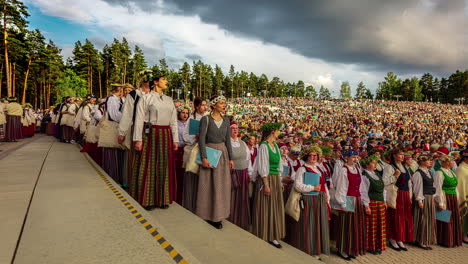 Timelapse-shot-of-group-performers-wearing-traditional-clothes-and-performing-during-Latvian-Song-and-Dance-Festival-in-an-outdoor-stadium-on-a-cloudy-evening