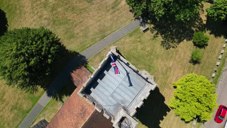 A-top-down-pan-of-a-union-flag-flying-from-the-tower-of-St-Mary's-church-in-Chartham