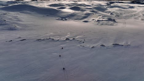Vista-Aérea-Del-Paisaje-Sobre-Personas-Montando-Motos-De-Nieve-En-El-Glaciar-Myrdalsjokull-En-Islandia,-Durante-Una-Puesta-De-Sol-épica