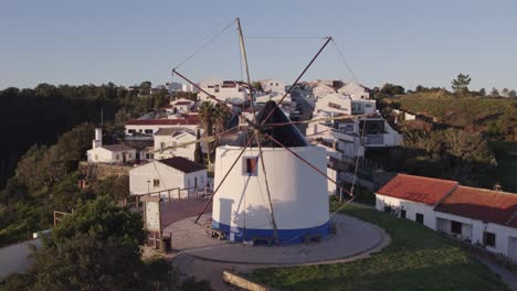 Fly-towards-typical-old-windmill-at-Odeceixe-Portugal,-aerial