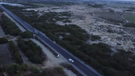 Aerial-view-of-cars-and-trucks-driving-down-a-desert-highway-in-beautiful-landscape-in-Balochistan