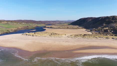 Reverse-aerial-shot-pulling-out-to-reveal-a-beautiful-beach-and-estuary-on-the-North-Coast-of-Scotland-on-a-beautiful-summer's-day
