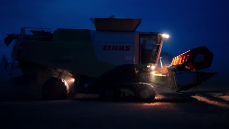 Combine-harvester-harvesting-grain-in-a-field-at-night-under-shining-spotlights
