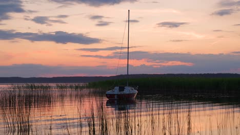 A-sailboat-anchored-in-a-picturesque-river-bay-during-sunset