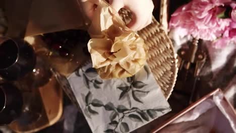 Close-up-of-female-hands-open-a-small-paper-bag-with-cheese-cut-into-cubes.-Wine-glasses.-Picnic-concept.-Footage-from-the-top
