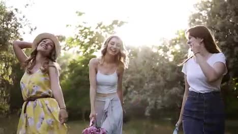 Three-beautiful-girls-on-a-bachelorette-party-in-nature.-Walking-in-the-green,-summer-forest.-Laughing,-jumping-freely.-Slow-motion