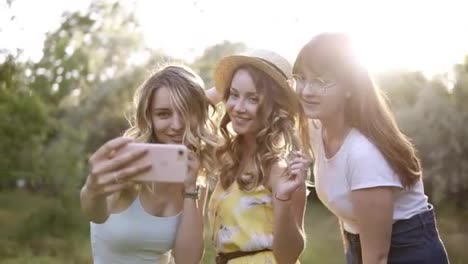Gruppe-Von-Drei-Schönen-Freundinnen,-Die-Draußen-Ein-Picknick-Machen.-Sie-Machen-Selfie-Fotos-Vom-Smartphone.-Die-Sonne-Scheint-Auf-Den-Hintergrund