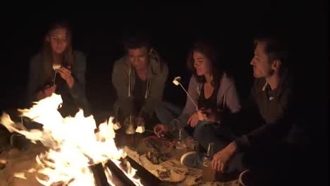 Beach-party-late-at-night-with-bonfire-and-roasting-marsh-mellows-with-friends
