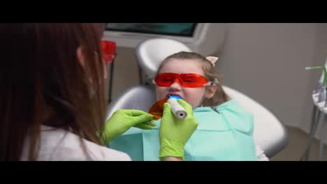 Kleines-Süßes-Mädchen-In-Der-Zahnarztpraxis-Bekommt-Eine-Zahnbehandlung,-Um-Eine-Lücke-In-Einem-Zahn-Zu-Füllen.-Zahnrestaurierung-Und-Materialpolymerisation-Mit-UV-Licht.-In-4k-Gedreht