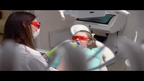 Kleines-Süßes-Mädchen-In-Der-Zahnarztpraxis-Bekommt-Eine-Zahnbehandlung,-Um-Eine-Lücke-In-Einem-Zahn-Zu-Füllen.-Zahnrestaurierung-Und-Materialpolymerisation-Mit-UV-Licht.-In-4k-Gedreht