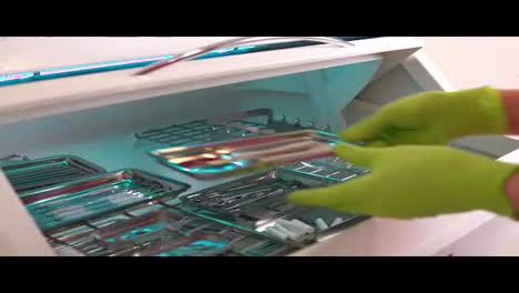 Close-up-shot-of-hands-in-gloves-taking-instruments-from-the-box-for-dental-instruments-disinfection.-Ultraviolet-sterile-chamber.-Shot-in-4k