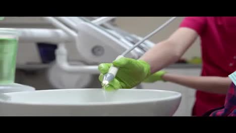 Closeup-view-of-dentist's-hand-preparing-her-instrument-for-utlrasound-cleaning.-Shot-in-4k