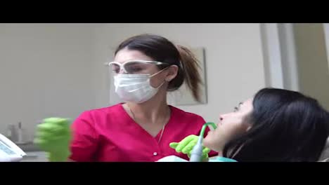 Woman-at-the-dental-hygienist-getting-professional-tooth-whitening-and-ultrasound-cleaning.-Dentist-using-saliva-ejector-or-dental-pump-to-evacuate-saliva.-Shot-in-4k