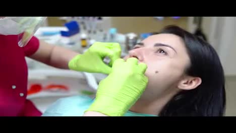 Nahaufnahme-Der-Hände-Des-Zahnarztes,-Die-Einen-Kofferdam-In-Den-Mund-Einer-Patientin-Stecken.-In-4k-Gedreht