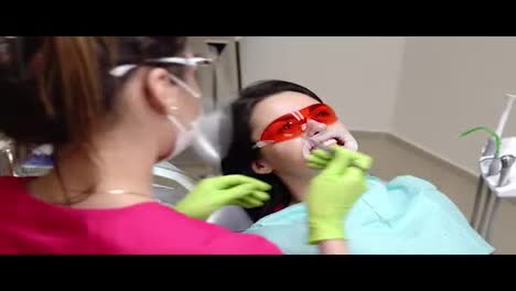 Young-woman-with-an-expander-in-mouth-at-the-dental-clinic.-Application-of-whitening-gel-to-the-teeth.-Modern-dental-office.-Shot-in-4k
