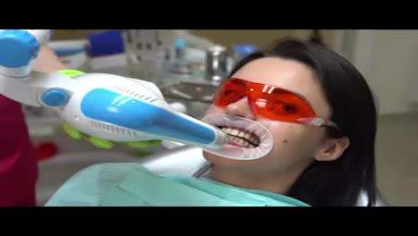 Young-woman-getting-UV-whitening-at-the-dentist's-office-by-an-ultra-violet-machine.-Shot-in-4k