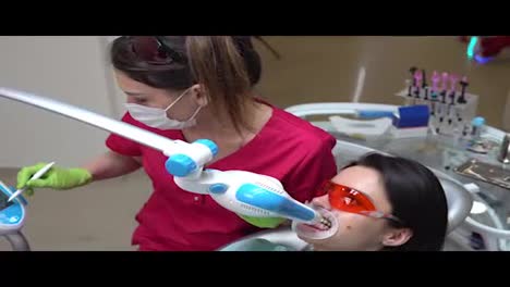 Junge-Frau-Lässt-Sich-In-Der-Zahnarztpraxis-Mit-Einem-UV-Gerät-UV-Bleaching-Aufhellen.-In-4k-Gedreht