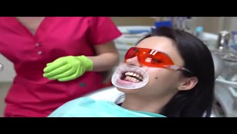 Female-dentist-taking-off-protective-glasses-and-mouth-expander-after-finishing-the-procedure-of-teeth-withening.-Shot-in-4k.