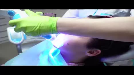 Junge-Frau-Mit-Einem-Expander-Im-Mund-Und-Roter-Schutzbrille-Lässt-Sich-In-Der-Zahnarztpraxis-UV-aufhellen