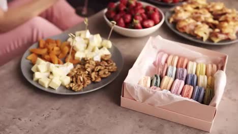 Close-up-footage-of-some-snacks-for-the-hen-party.-A-luxurious-way-of-life.-Macaroons,-canap-,-strawberry-on-a-wooden-coffee-table