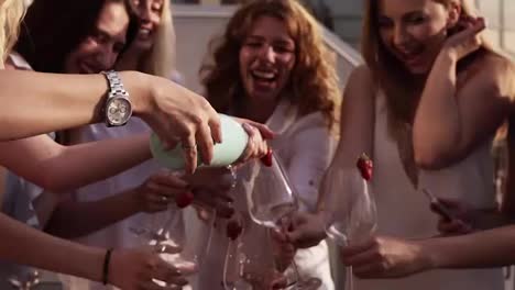 Beautiful-young-ladies-celebrate.-Hen-party.-Shaking-a-bizarre-bottle-of-champagne-and-letting-it-spraying.-The-girl-pours-a-drink-into-glasses.-Outside.-Glamorous-party.-Slow-motion