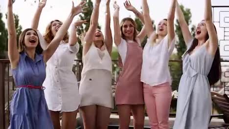 Stylish-girls-on-bachelorette-party-outside-on-the-terrace.-Throw-silver-confetti-into-the-air.-Happy-lifestyle,-enjoy-life.-Dancing-and-laughing.-Daytime.-Slow-motion