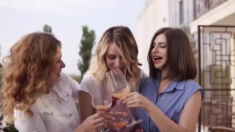 Concept-of-hen-party.-Three-beautiful-women-drinking-cocktails-together-on-a-terrace.-Women-chatting-and-laughing.-Slow-motion