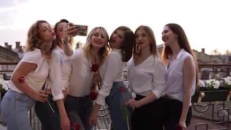 Close-up-of-a-seductive,-young-women-taking-selfie-outdoors-on-a-terrace.-Happy,-cheerful-girls-in-white-casual-clothes.-Sun-shines-on-a-background.-Hen-party-concept