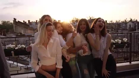 Close-up-of-fashionable-girls-in-the-same-casual-clothes-seductively-dancing,-posing-in-front-of-the-camera-on-the-terrace.-Evening-dusk