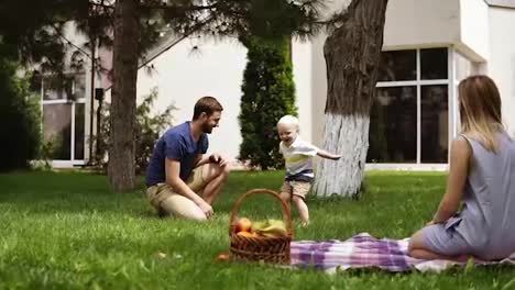 Caucasian-family.-Father-amusing-his-little-son,-throwing-cones-to-the-air.-Hanging-out-in-the-park.-Picnic-concept.-Slow-motion